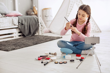 First experiments. Adorable pre-teen girl sitting cross-legged on the floor and testing a new...