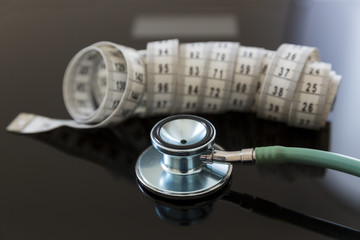 Stethoscope and measuring tape on scales. Safe weight losing concept. Dieting under supervision