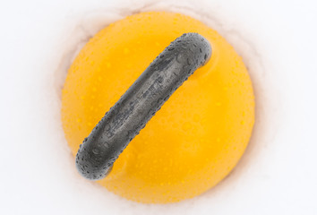 Top view of a yellow weight training kettlebell covered with water droplets outside in the snow. Yellow competition kettlebells weigh 16kg.