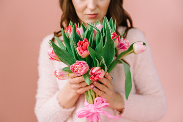 A girl in a pink room with a bouquet of tulips in her hands