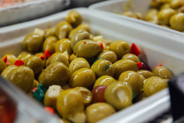 Olives in dressing with oil and peppers in market