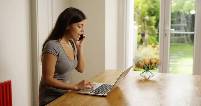 4K Confident businesswoman working on laptop at home & making a phone call. Slow motion.