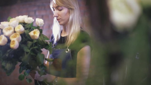 Girl florist makes a bouquet in a floral shop