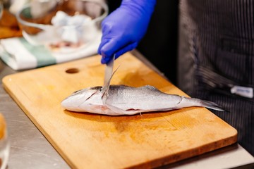 Woman cook preparing and cleaning raw dorada fish