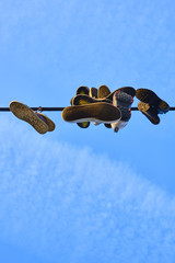 Old Shoes hanging on electrical wire against a sky. Shoe tossing
