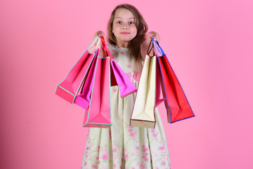 Schoolgirl with red, pink and yellow packets does shopping