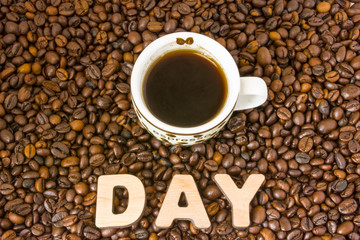 Coffee Day photo. Cup with brewed coffee is on table, which filled with roasted coffee beans, next to word break. Idea for global International Coffee Day or other events or celebration