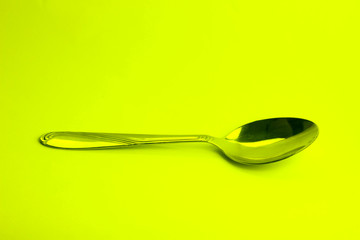 metal spoon close-up isolated on yelow background