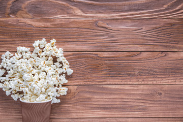 Fototapeta premium Popcorn in brown paper cups on rustic wooden background with copy space, top view, flat lay. Cinema concept.