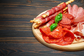 Cold smoked meat plate with pork chops, prosciutto, salami and bread sticks