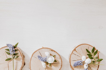 Spring Easter decoration with wooden blocks with grape hyacinths, little eggs and green leaves on the bottom of white wooden table