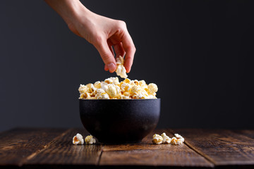 A full bowl of popcorn and the hand that takes it.