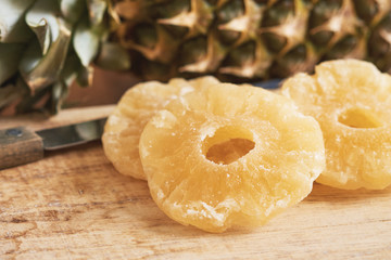 Dried and candied pineapple rings on wooden background