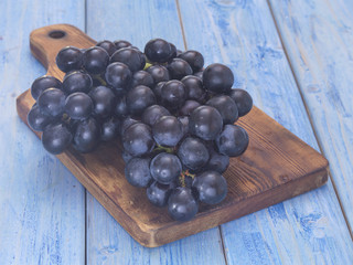 black grapes on a blue wooden background. 
