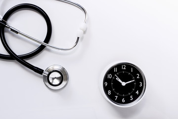 Stethoscope with a clock on white table background. The stethoscope is a medical instrument for listening to the action of someone's heart or breathing.