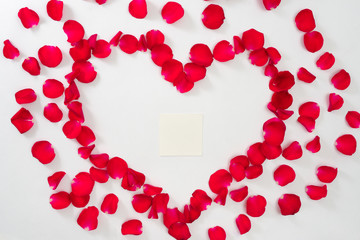 Heart of red rose petals on white background.