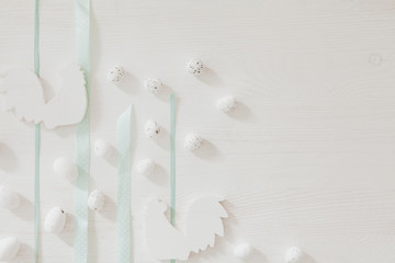 Easter blue ribbons on white wooden table with little easter eggs and rooster