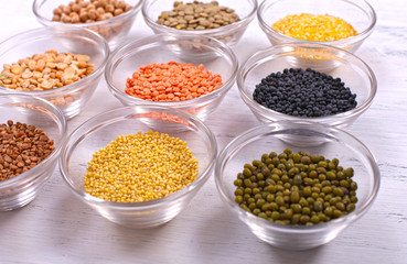 Assorted healthy organic cereals in bowls on white wooden background.