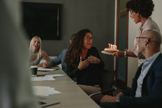 Coworkers celebrating birthday of female colleague with cake