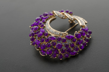golden round brooch with purple diamonds isolated on black