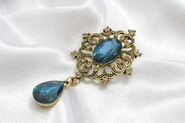 golden vintage brooch with blue stone on silk
