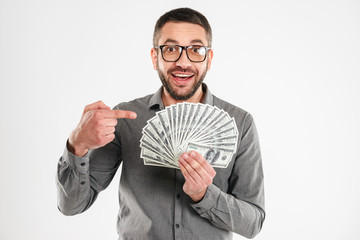 Excited businessman holding money pointing.