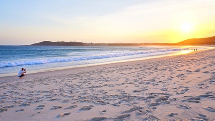 Mann fotografiert Sonnenuntergang in Byron Bay am Strand - Australien