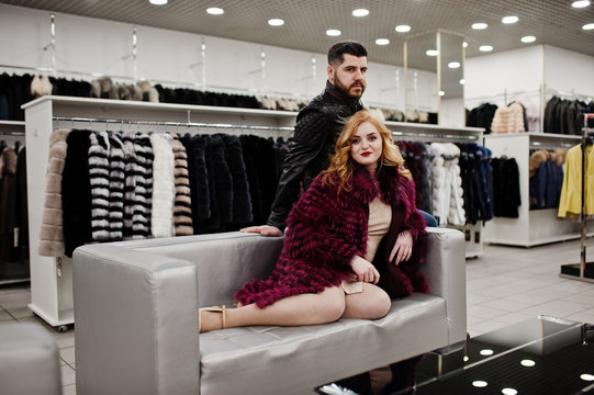 Elegance blonde girl in fur coat and stylish turkish man at the store of fur coats and leather jackets.
