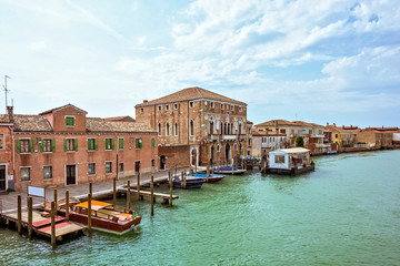 Daylight view to Venetian Lagoon canal with parked boats