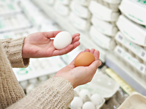 Hands of woman with white and brown eggs in store