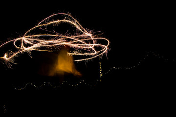 A young woman playing with sparklers at night creating a random pattern.
