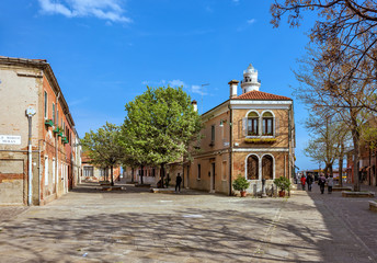 Daylight view to green square with trees and people walking