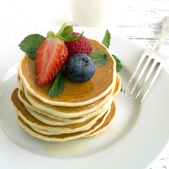 American pancakes with berries on a light background.