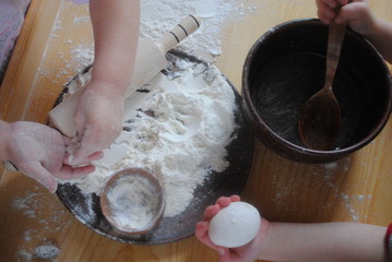 Children's rolling pin for dough. The child kneads the dough with his hands. The baby's hand sifts the flour.