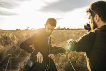 Back view of videographer with camera taking videos of handsome bearded man.