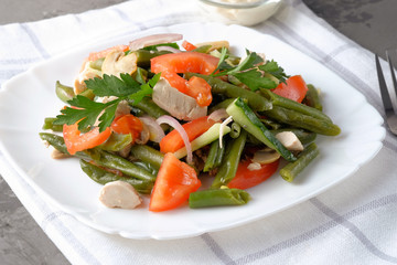 Spring salad of chicken breast, mushrooms, black-eyed peas, cucumbers, tomatoes and onions on a white plate. Healthy eating.