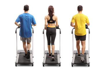 Fototapeta na wymiar Two young men and a woman exercising on treadmills