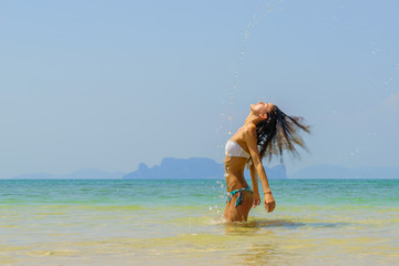 Naklejka premium Beautiful girl splashing water with her hair in the sea.