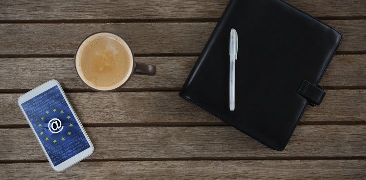 Composite image of mobile phone, coffee, pen and organizer on