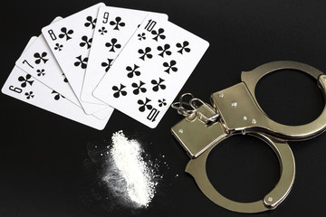poker game. illegal casino arrest. handcuffs, drug and poker cards.