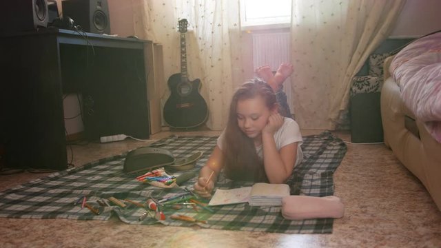 Girl teen who spend time at home drawing while lying on the floor