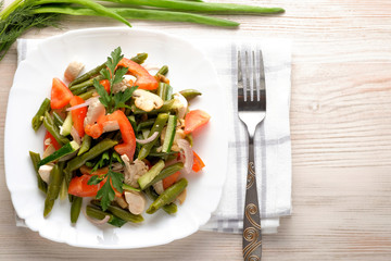 Spring salad of chicken breast, mushrooms, black-eyed peas, cucumbers, tomatoes and onions on a white plate. Healthy food, top view.