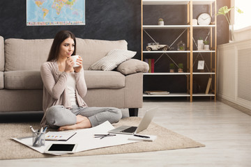 Thoughtful woman drinking coffe while working