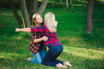 two young women sitting on grass hugging