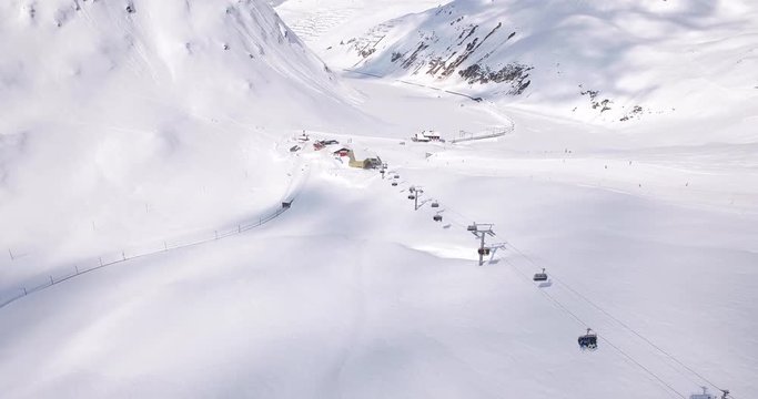 Aerial establishing shot of slopes, ski lifts on a ski resort in the Swiss Alps