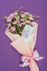 beautiful floral bouquet with pink ribbon and greeting card on violet