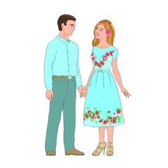 A young guy in trousers and a shirt stands with a girl in a blue dress. He holds her hand and lovingly looking at her.