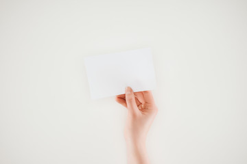 cropped shot of woman holding blank sheet of paper isolated on white