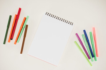 top view of blank notepad with colorful markers isolated on white