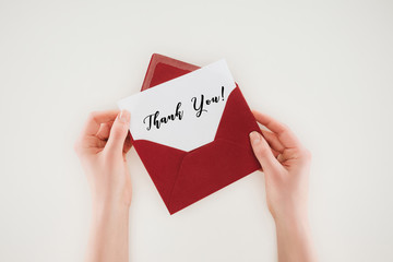cropped shot of woman opening red envelope with thank you lettering on paper isolated on white